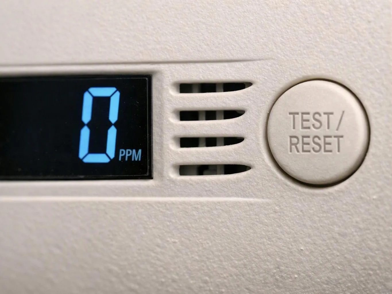 Close-up of a smoke detector display showing “0 PPM” beside a TEST/RESET button and вентиляционные slots